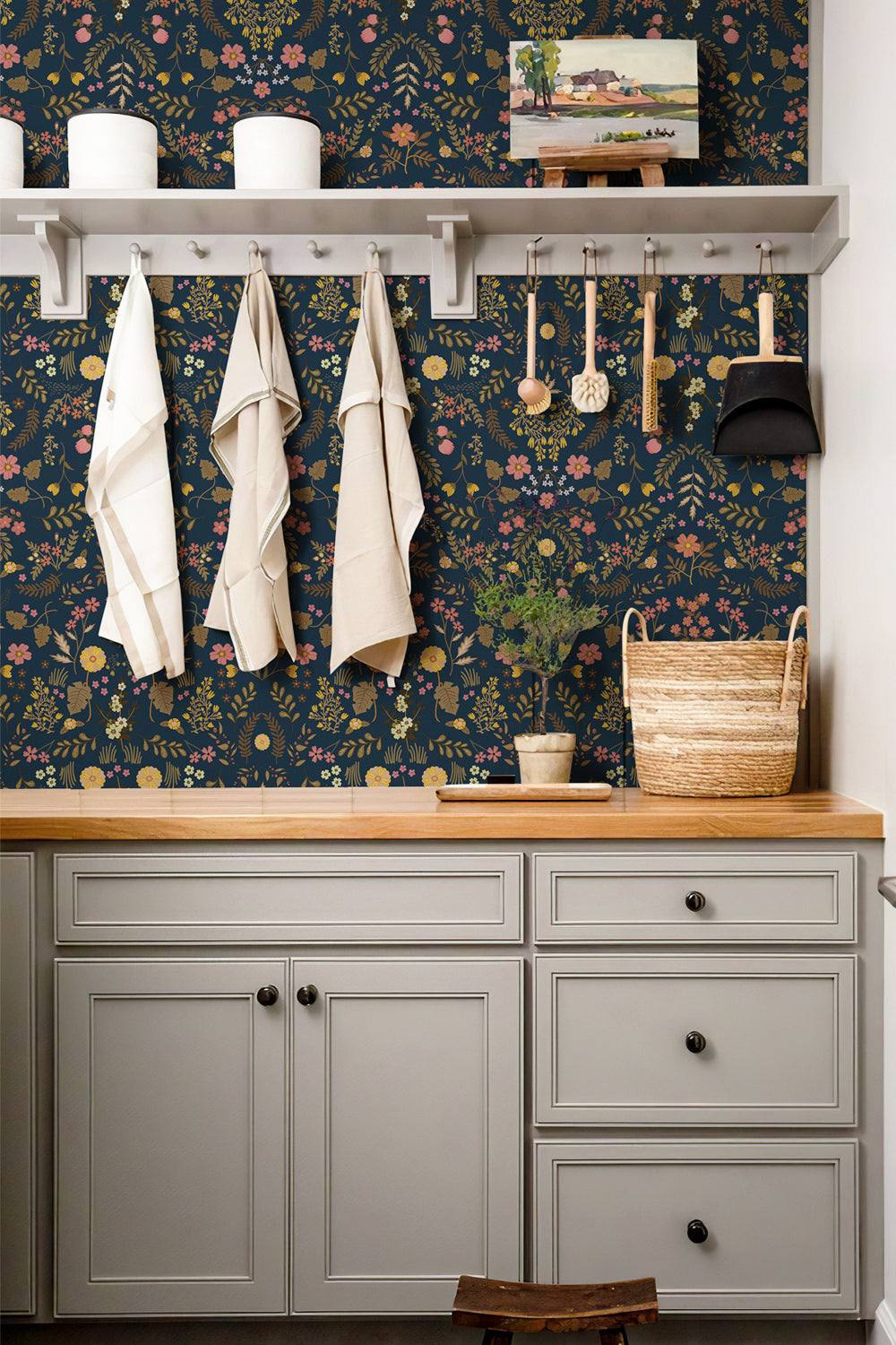 Vintage wildflower wallpaper decorates the stairwell wall. The rich floral pattern matches dark‑wood stair handrail, creating an elegant cottage‑style entryway atmosphere.