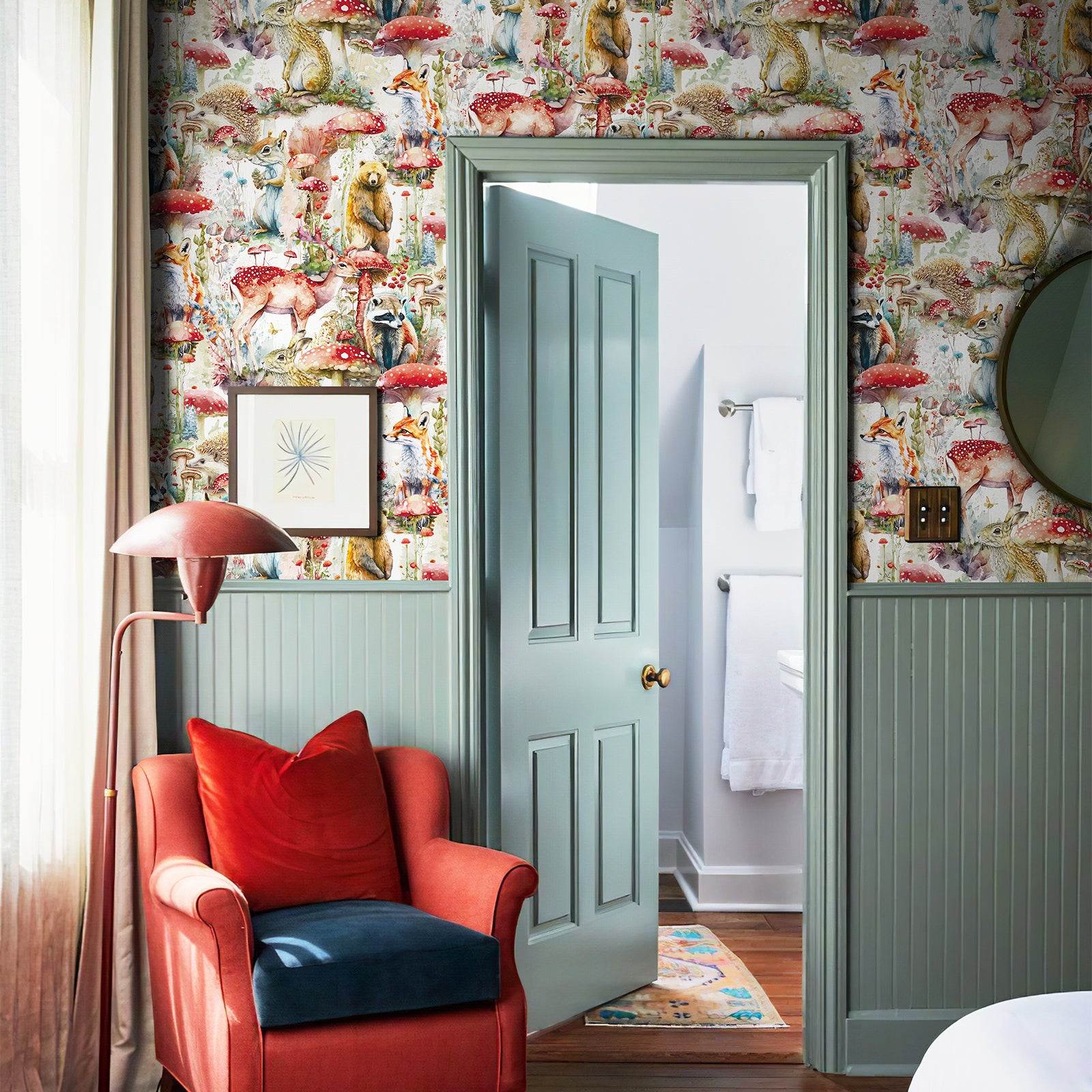Fairy‑tale forest wallpaper covers the wall around the bedroom doorway, paired with green wainscoting and a red accent armchair for a warm playful entry nook.